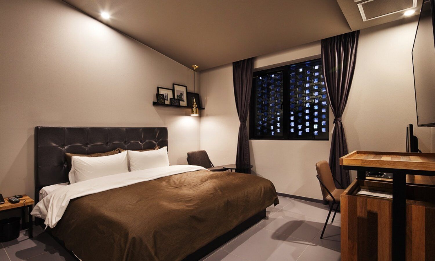 Una camera d'albergo moderna con un letto grande, una scrivania e una finestra con tende.