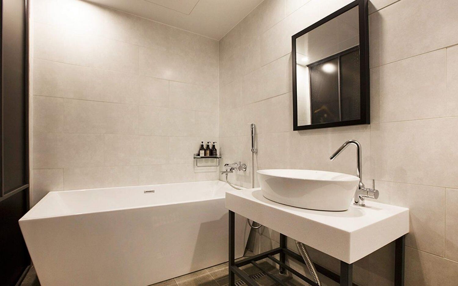 A modern bathroom with a large bathtub, a white sink, and a mirror above the sink.