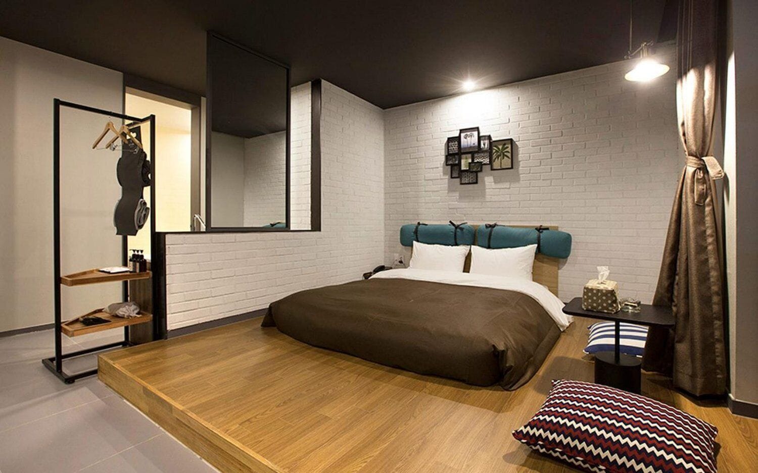 A modern bedroom with a bed, a wardrobe, a mirror, and a bedside table.