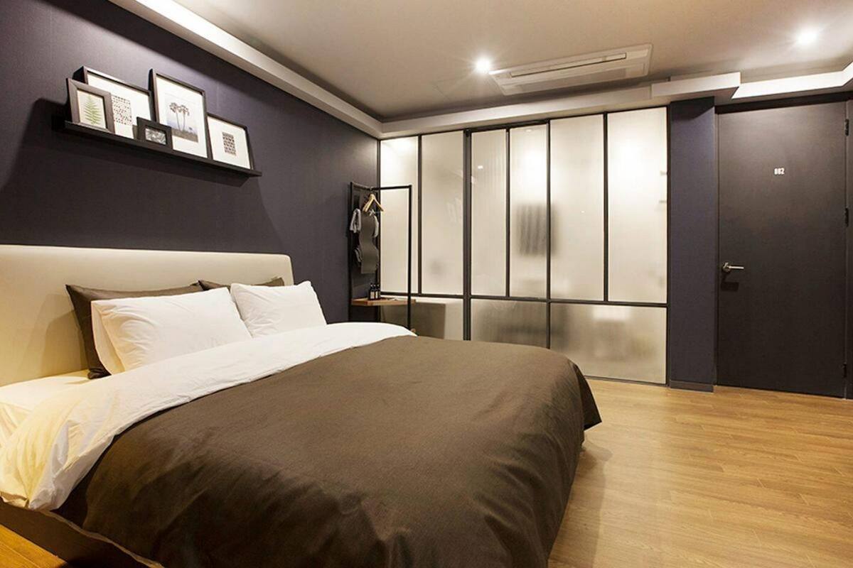 Quarto moderno com uma cama grande, um guarda-roupa com portas deslizantes e uma coleção de quadros na parede.