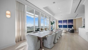 A spacious room with a long table and chairs, large windows with a city view, and a modern ceiling design. - Tresor 2-3702 (Miami Beach)