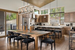 A spacious kitchen with wooden cabinets, a central island, and large windows offering a view of the outdoors. - Lakota SkiRenity | Outdoor Fire Pit | Private Hot Tub w/ Resort Views (Winter Park)