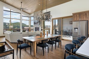 A spacious living area with a large window, a fireplace, and a dining table with chairs. - Lakota SkiRenity | Outdoor Fire Pit | Private Hot Tub w/ Resort Views (Winter Park)