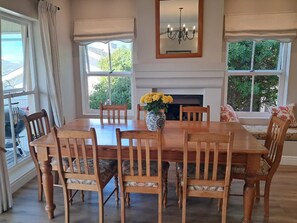 Uma sala de jantar com mesa e cadeiras de madeira, um vaso com flores e uma lareira.