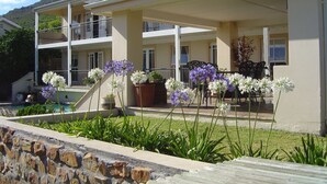 Un edificio de dos pisos con balcón, piscina y plantas en macetas.