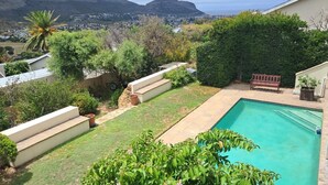 Patio con piscina, una banca y vistas a un pueblo y montañas.