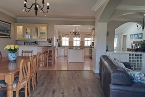 A spacious kitchen with wooden cabinets, a dining area with a table and chairs, and a living area with a sofa. - The Lookout 3 Bedroom Home in Fish Hoek (Cape Town)