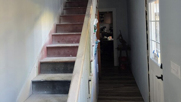 Eine Treppe führt zu einer Zwischenebene mit einer Tür und einem Fenster.