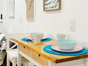 A dining table with plates, bowls, and a cup, set on a wooden table with a blue placemat. - Clean GATED BeachBoho Private Tiny Suite AC/Heat WasherDryer by LAX+Beach+SoFi (Inglewood)