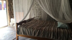 Un lit avec une couvre-lit à rayures, une tête de lit en bois et un baldaquin.