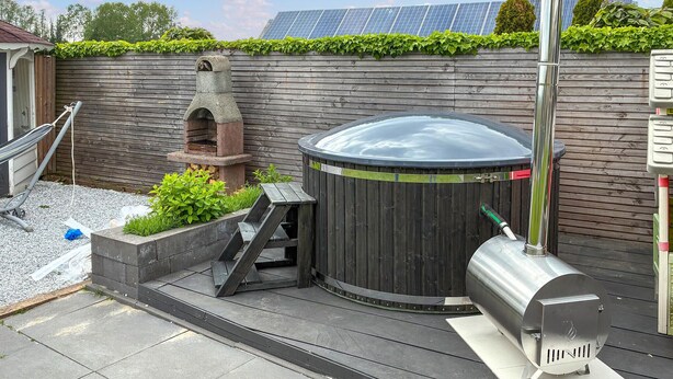 A backyard with a hot tub, a grill, and a stone oven.