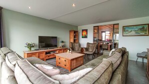 A living room with a sofa set, a TV, a coffee table, and a dining area with chairs and a table.