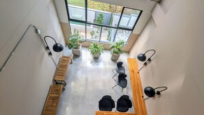 A modern waiting area with a staircase, wooden benches, black chairs, potted plants, and a large window offering a view of the outdoors. - Comfortable private apartment near the Tennis Club in Cali salsa city with AC. (Cali)