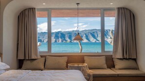 Une chambre avec une grande fenêtre, un lit, un canapé et une lampe suspendue.