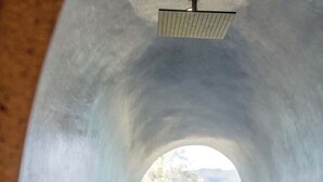 Une salle de spa dotée d’une fenêtre circulaire, d’une douche et d’une baignoire.