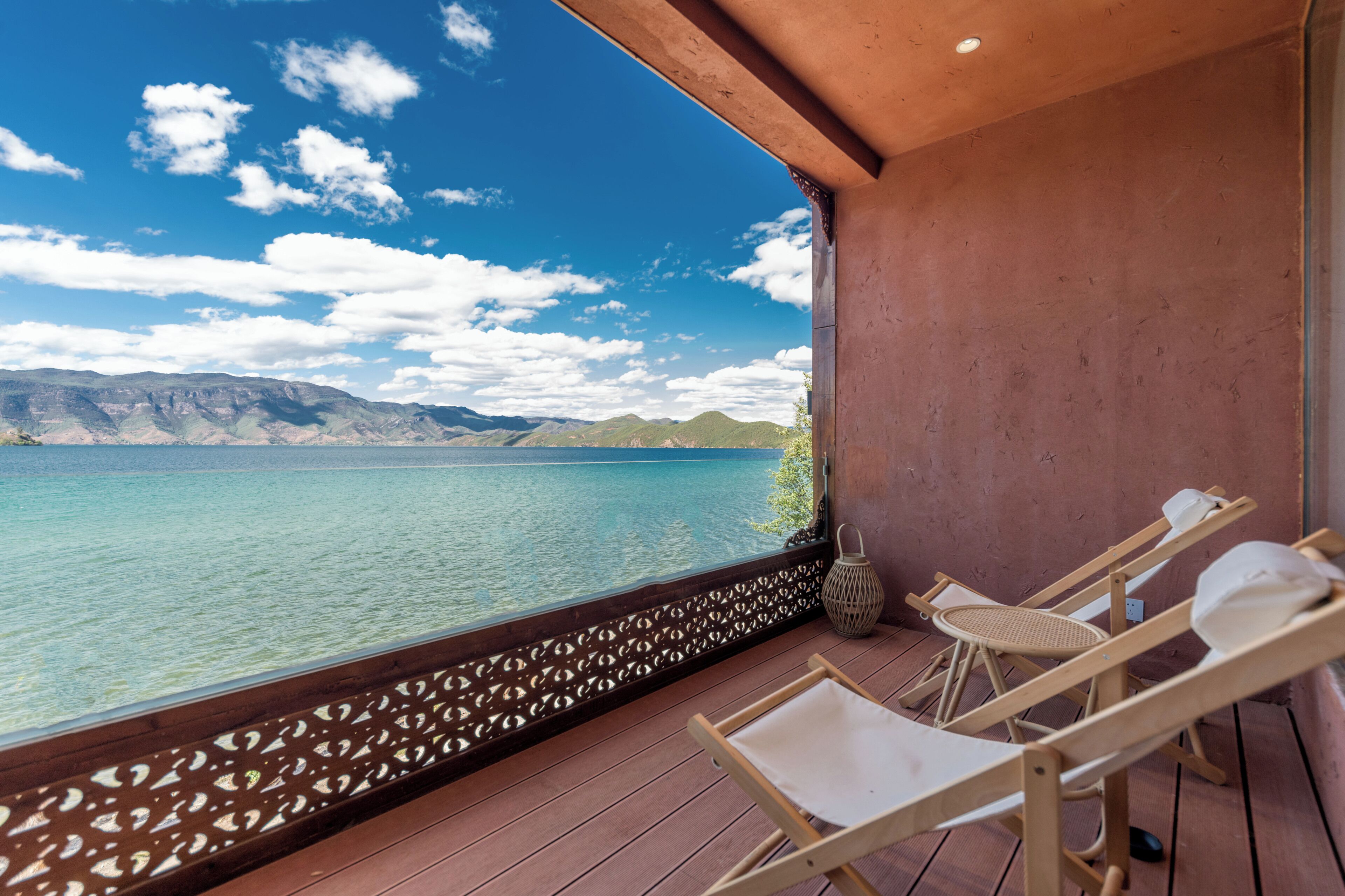 Un balcone con vista su un lago e montagne, arredi in legno e un pannello decorativo a parete.