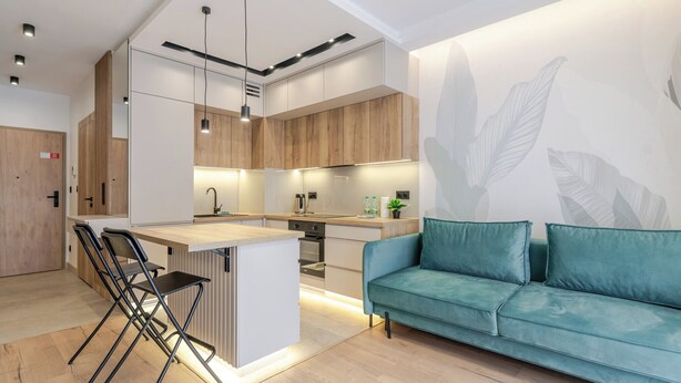 Eine moderne Küche mit Holzausstattung, einer Mittelinsel und einem blaugrünen Sofa.
