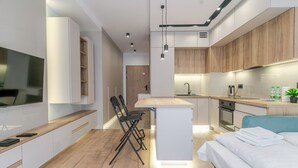 Eine moderne Küche mit einer zentralen Kochinsel, einem Essbereich mit Stühlen, einem eingebauten Ofen und einem Bett mit blauer Kopfteil.