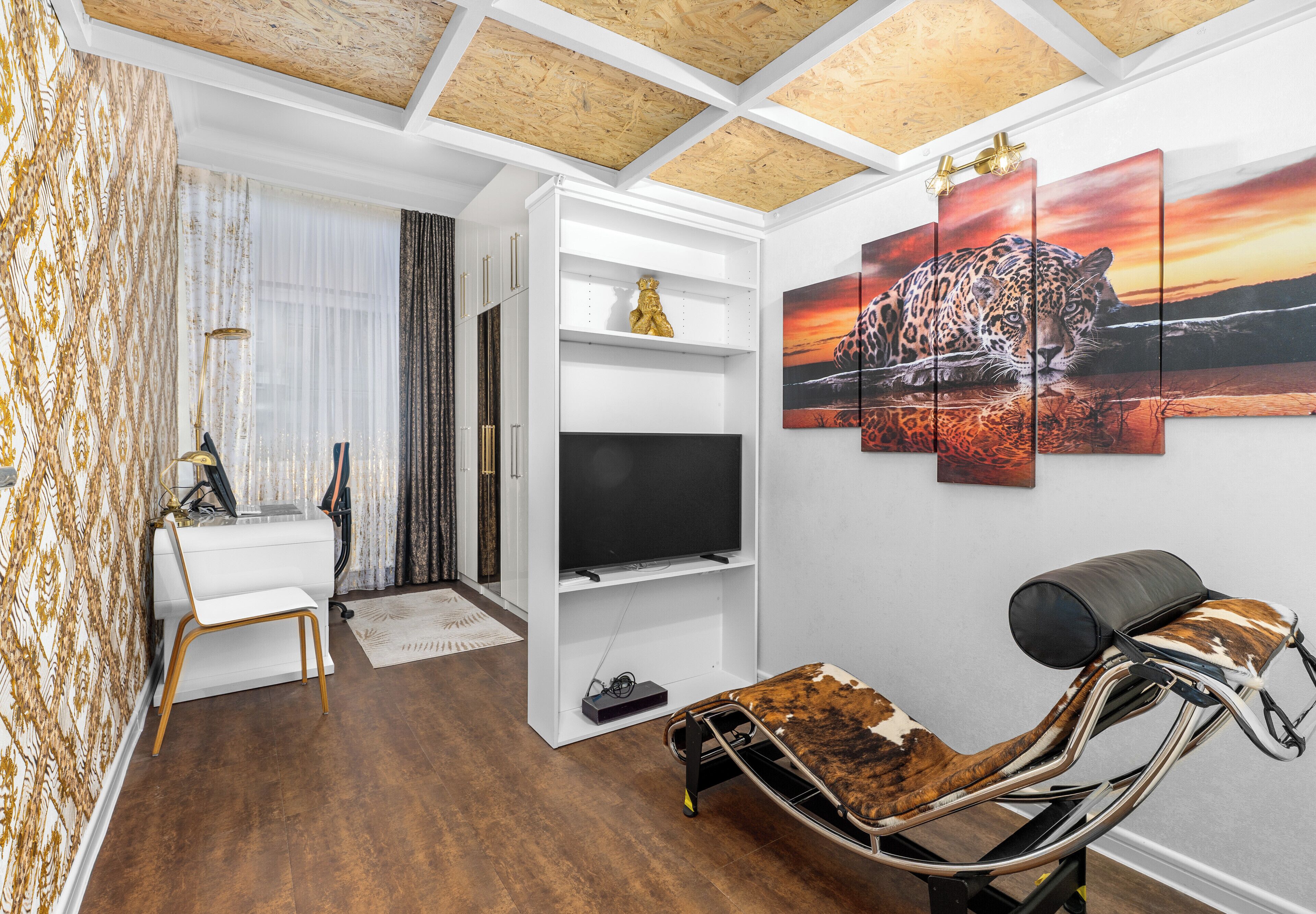 A modern living room with a TV, a sofa, a chair, and a wall art piece of a leopard.