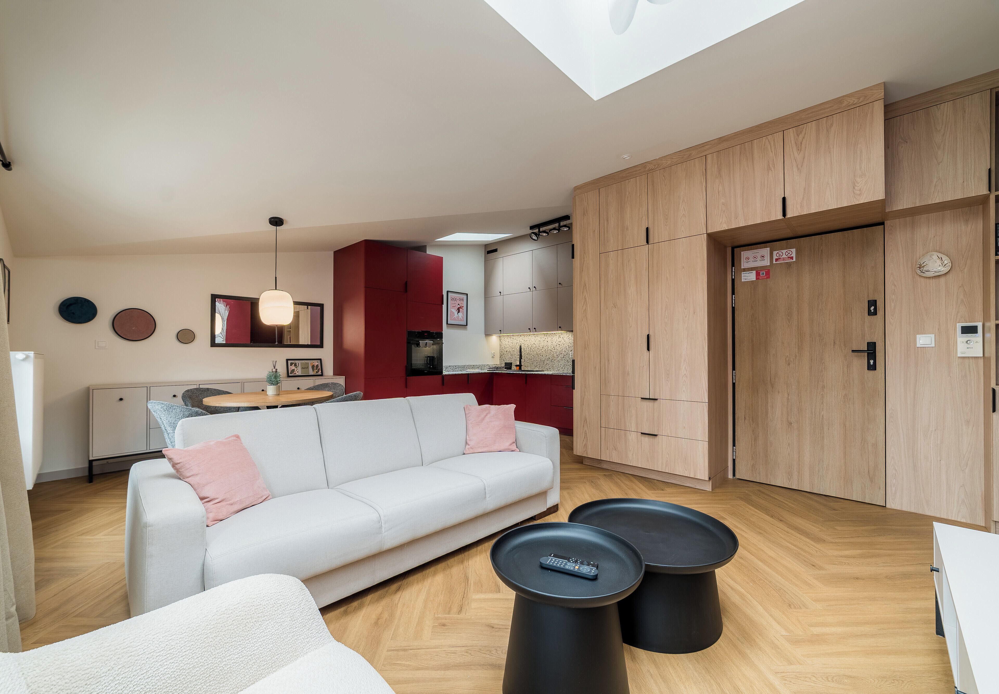 Un espacio de estar moderno con sofá, mesa de centro y una cocina con armarios y mesa de comedor.