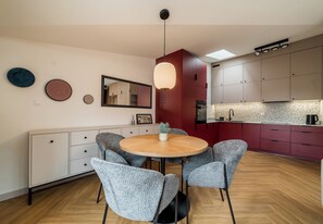 Cuina moderna amb taula rodona, cadires tapissades de color gris i una l àmpada penjant.