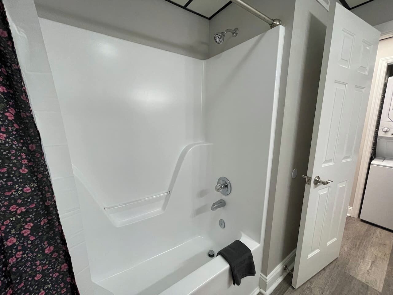 A bathroom with a bathtub, shower, and a door leading to another room.