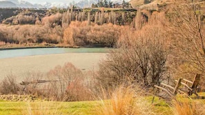 A river with a wooden fence in the foreground. - Toi Point Lodge - A rural luxury villa inspired by the charm of a historic stone farm building. (Queenstown)
