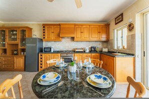 A kitchen with wooden cabinets, a granite countertop, and a dining table set for six. - Romantic Gozo Escape Private Pool Terrace BBQ (Xaghra)