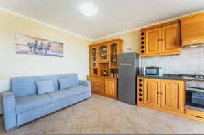 A kitchen with wooden cabinets, a refrigerator, a microwave, and a sofa. - Romantic Gozo Escape Private Pool Terrace BBQ (Xaghra)