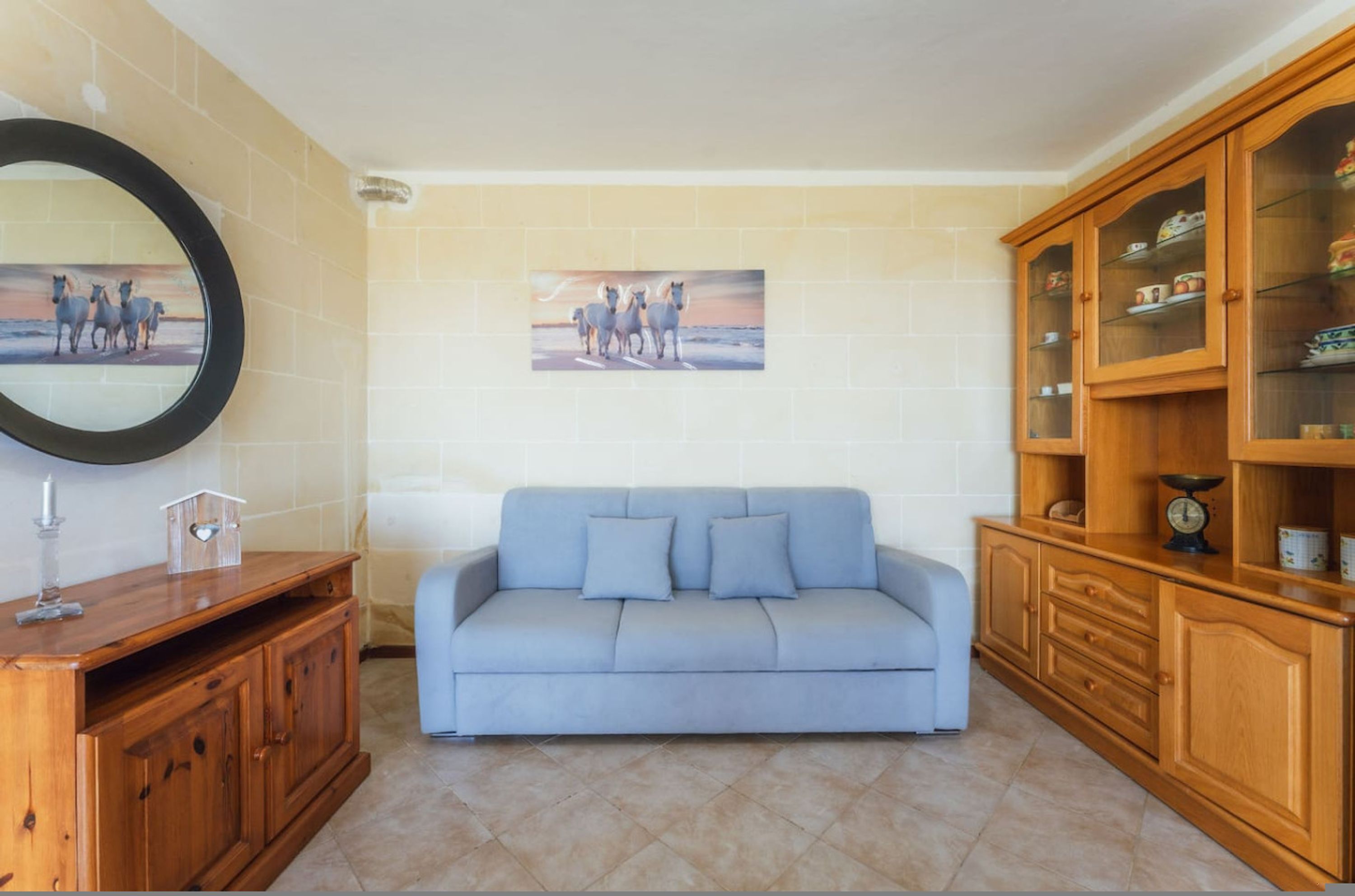Un salon avec un canapé, un meuble en bois et un miroir fixé au mur.