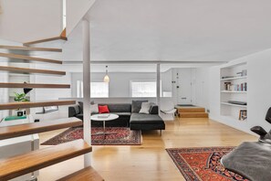 Ein modernes Wohnzimmer mit einer Couch, einem Couchtisch und einer Treppe mit Holzwandungen.