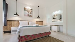 Een hotelkamer met een bed, nachtkastje, lamp, spiegel en kunstwerk aan de muur.