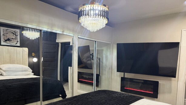 Une chambre moderne avec un grand lit, une télévision, un miroir et un lustre.