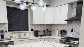 Une cuisine moderne dotée d’un îlot central, de tabourets de bar, d’une cuisinière et d’un espace dédié à la préparation du café.