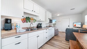 Eine moderne Küche mit weißen Schränken, einer Granit-Arbeitsplatte und einer eingebauten Mikrowelle.