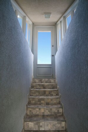 Una escala amb vistes a l'exterior, emmarcada per parets amb acabat texturat.