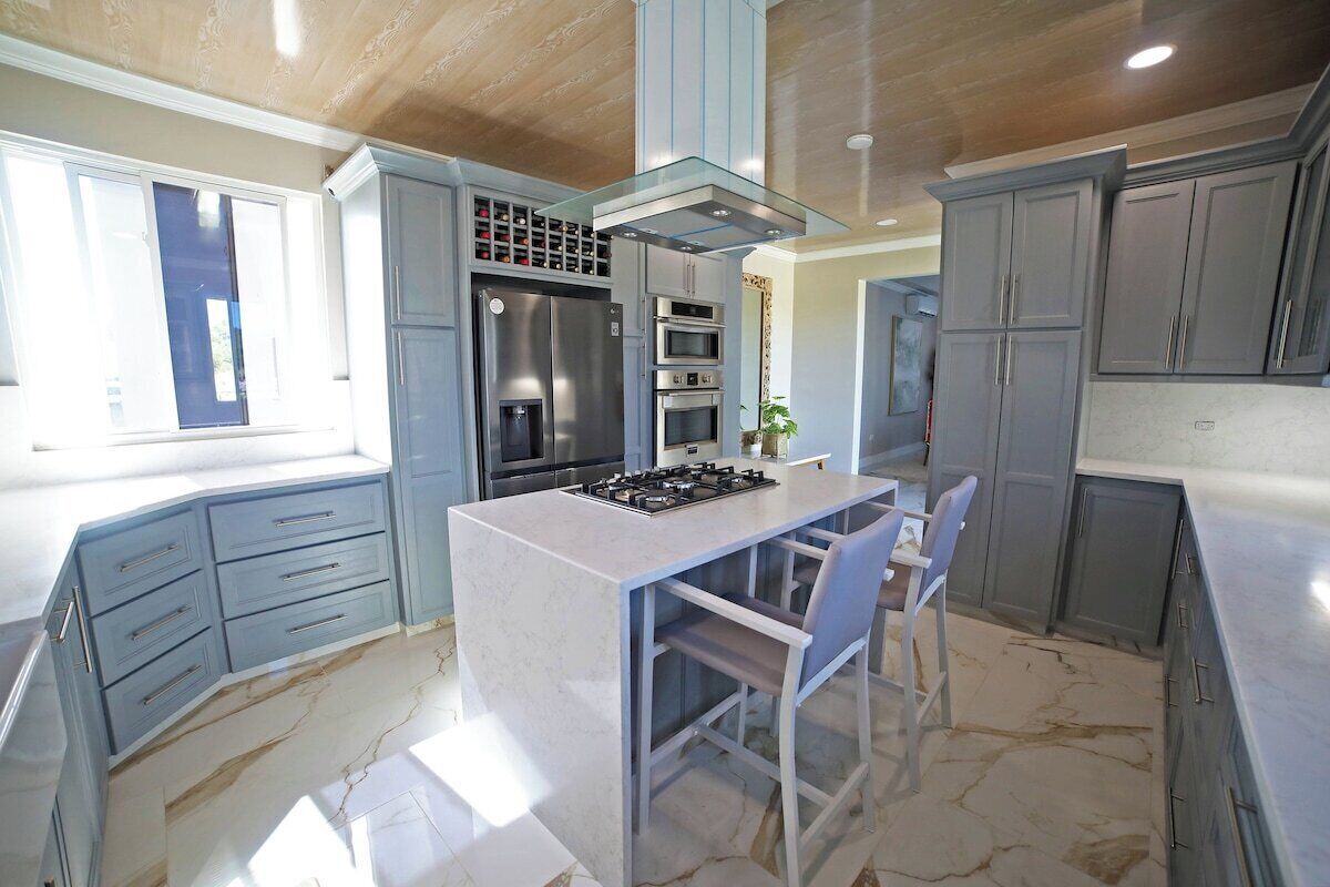 Una cucina moderna con isola centrale, elettrodomestici integrati e mobili grigi.