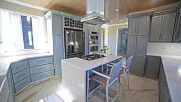 Una cucina moderna con isola centrale, elettrodomestici integrati e mobili grigi.