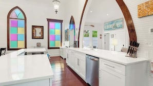 A modern kitchen with a central island, white cabinetry, and a large mirror.