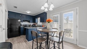 Una cucina moderna con mobili blu scuro, un frigorifero nero e un tavolo da pranzo rotondo con quattro sedie.
