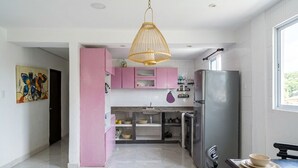 A modern kitchen with white cabinets, a pink accent wall, a large refrigerator, and a hanging pendant light. - Room +Wifi +Air conditioning. cozy, close to supermarket, Oxxo. (Barranquilla)
