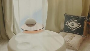 A bed with a white headboard, a round bedside table, and a pillow with a geometric pattern. - Shonan Minpaku Kabigon (Chigasaki)