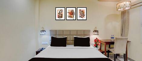 Habitación de hotel con cama, escritorio y una silla. Tres cuadros enmarcados adornan la pared.