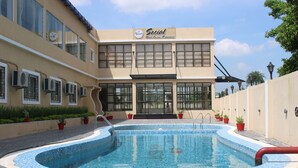 A building with a swimming pool, air conditioning units, and potted plants. - Amar Resorrt Motihari Bihar (Motihari)