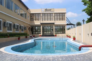 Un edificio con piscina, aire acondicionado y plantas en macetas.