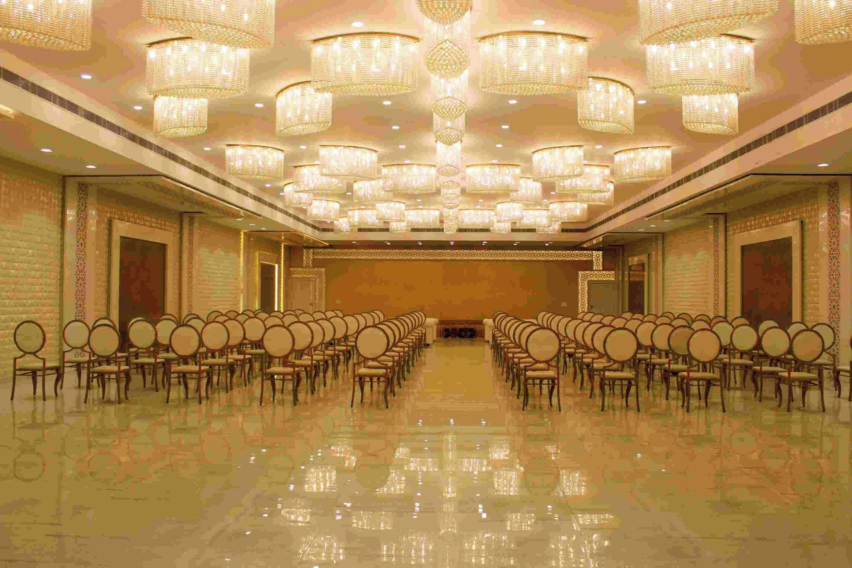 A spacious hall with rows of chairs and ornate chandeliers.