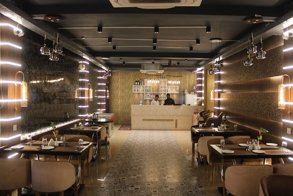 A restaurant with a central counter, multiple tables, and hanging light fixtures.