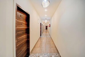A hallway with a wooden door marked '210', a patterned floor, and a ceiling light fixture. - Amar Resorrt Motihari Bihar (Motihari)