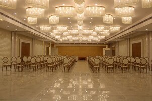 Un salón amplio con filas de sillas, candelabros ornamentados y un piso pulido.