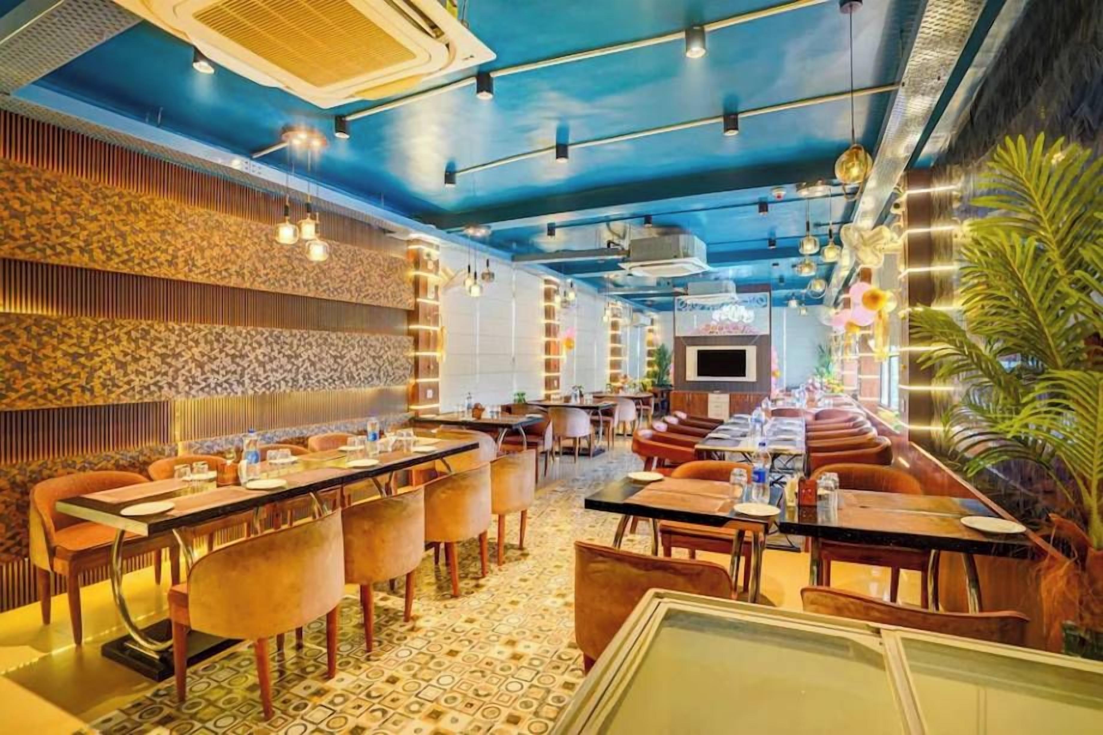 A restaurant with a blue ceiling, patterned walls, and a variety of seating arrangements including tables and booths.